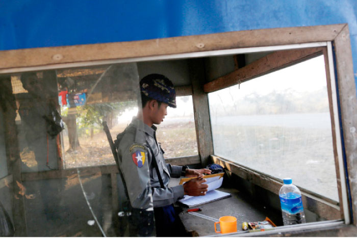 A Myanmar policeman stands in a check point outside Rohingya refugee camp in Sittwe, Myanmar. — Reuters