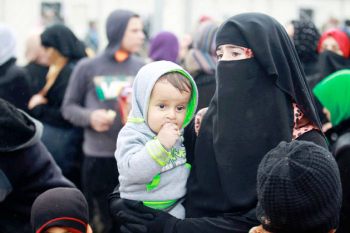 A displaced Iraqi woman carries her child at Hammam Al-Alil camp, as Iraqi forces battle with Daesh militants in Mosul, Iraq. — Reuters