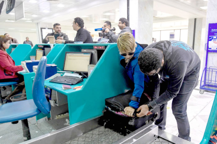 A Tunisian couple bound for London pack away their electronics in their luggage as they check-in for a flight at Tunis-Carthage International Airport on Saturday. — AFP