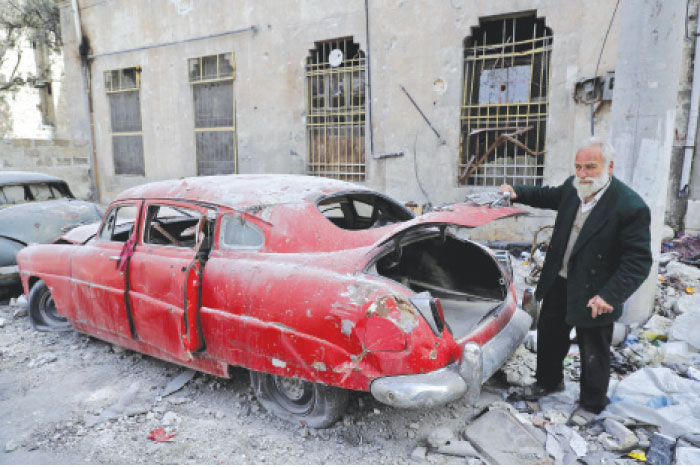 A picture taken on March 9, 2017, shows 70-year-old Mohammad Mohiedine Anis opening the trunk of his 1949 Hudson Commodor outside his home in Aleppo›s formerly rebel-held Al-Shaar neighborhood. — AFP