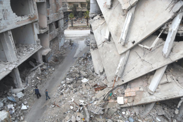 Syrian boys walk amidst destroyed buildings in the Syrian rebel-held town of Arbin, in the eastern Ghouta region on the outskirts of the capital Damascus. — AFP