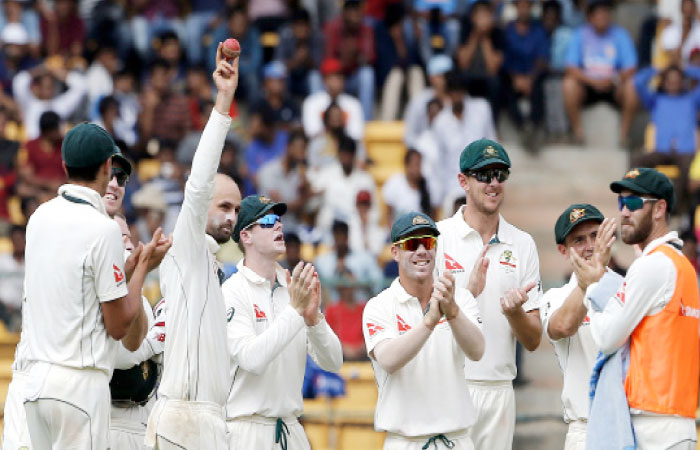 Australia’s Nathan Lyon, without cap, holds the ball as his teammates clap their hands during the first day of their second Test cricket match against India in Bangalore Saturday. —AP