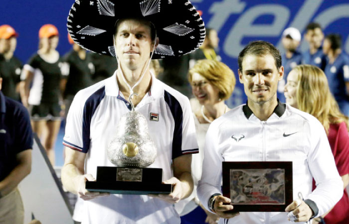 Sam Querrey (L) of the US holds the winner’s trophy after winning his final against Rafael Nadal of Spain in Acapulco Saturday. — Reuters
