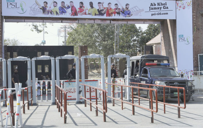 Pakistani police officers stand guard beside walk through metal detector specially installed at an entry gate of Gaddafi Stadium for the final cricket match of Pakistan Super League, in Lahore, Saturday. — AP