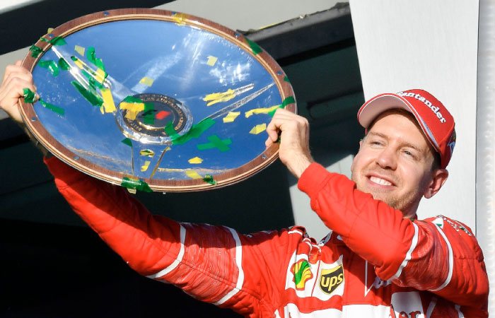 Ferrari’s German driver Sebastian Vettel celebrates with the winner’s trophy on the podium following his victory in the Australian Grand Prix in Melbourne Sunday. — AFP