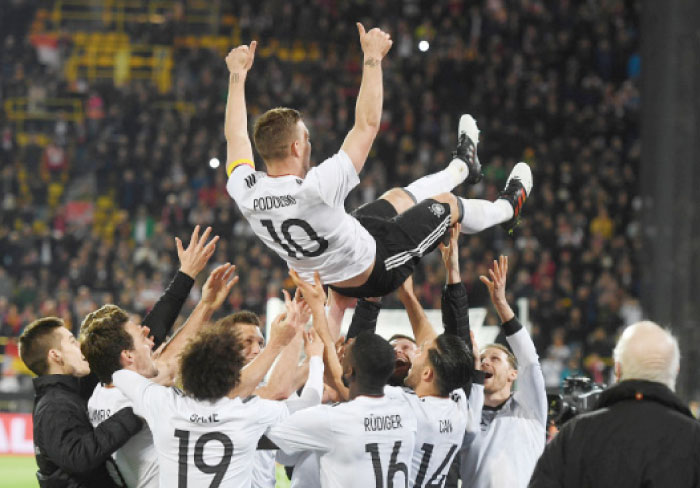 Teammates throw Germany’s Lukas Podolski in the air after their friendly football match against England in Dortmund Wednesday. It was Podolski’s last match with the German team. — AFP