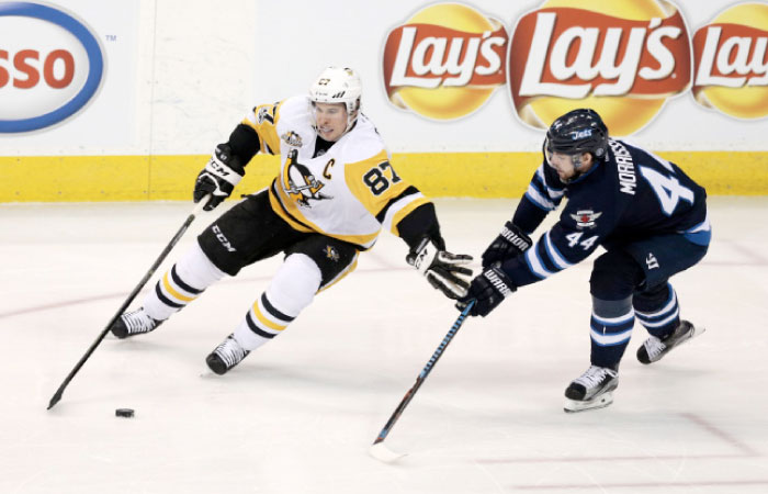 Penguins’ center Sidney Crosby (L) controls the puck against Winnipeg Jets’ defenseman Josh Morrissey during their NHL game at MTS Centre in Winnipeg Wednesday. — AP