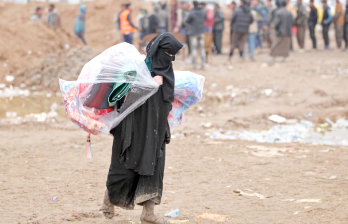 A displaced Iraqi woman carries blankets at the Hamam al-Alil camp, where many residents from Mosul are taking shelter, as the government forces continue their offensive to retake the embattled city from Daesh (the so-called IS) fighters on Sunday. — AFP