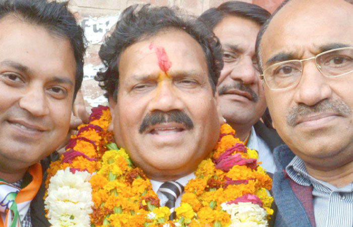 Congress Party candidate for the Punjab Legislative Assembly, Raj Kumar, center, hold flowers presented by his supporters after the announcement of results in his favor outside a counting center in Amritsar, Punjab, on Saturday. — AFP