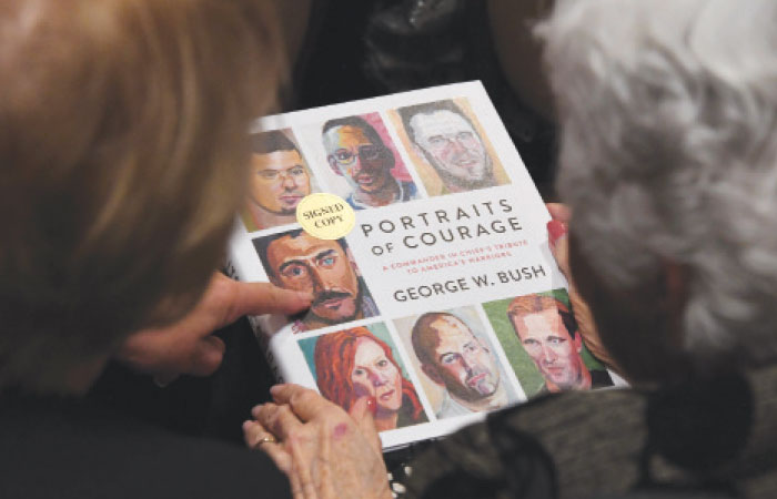 Members of the audience view the book by former US president George W. Bush before he spoke at the Ronald Reagan Presidential Library to promotes his book “Portraits of Courage: A Commander in Chief’s Tribute to America’s Warriors” in California, Wednesday. — AFP