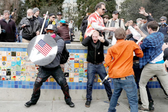 A demonstrator supporting US President Donald Trump, left, holds a shield as a group of men punch a counter demonstrator during a “People 4 Trump” rally in Berkeley, California, on Saturday. — Reuters