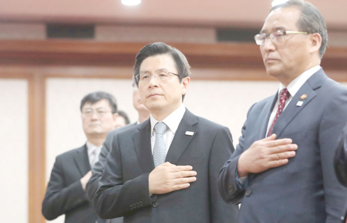 South Korean Prime Minister and acting President Hwang Kyo-ahn, center, salutes to the national flag at a Cabinet meeting in Seoul on Wednesday. — Reuters