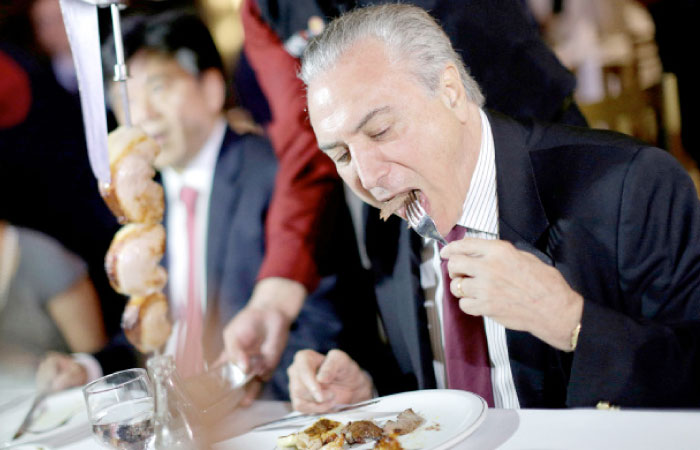 Brazil’s President Michel Temer eats barbecue in a steak house after a meeting with ambassadors of meat importing countries of Brazil, in Brasilia, Brazil, on Sunday. — Reuters