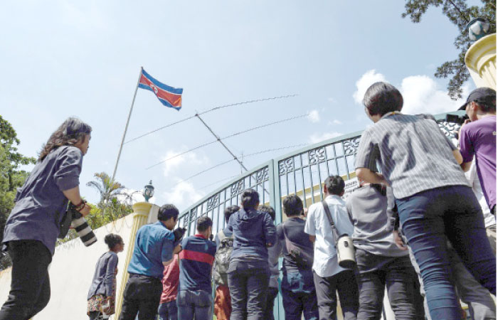 Members of the media film crowd outside the gate of the North Korean embassy in Kuala Lumpur on Monday. — AFP