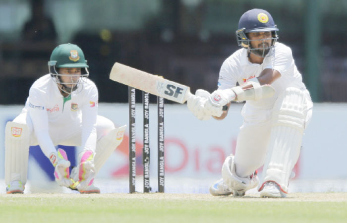 Sri Lanka’s Dinesh Chandimal (R) plays a shot as Bangladeshi wicketkeeper Mushfiqur Rahim watches on day one of their second Test cricket match in Colombo Wednesday. — AP