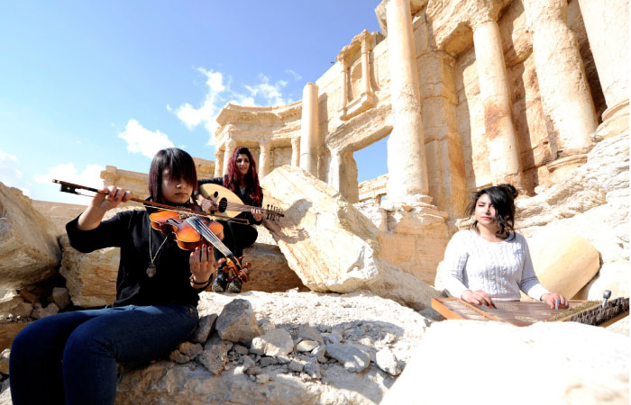 Syrian musicians play their instruments while resting on damage in the amphitheater of the historic city of Palmyra. — Reuters