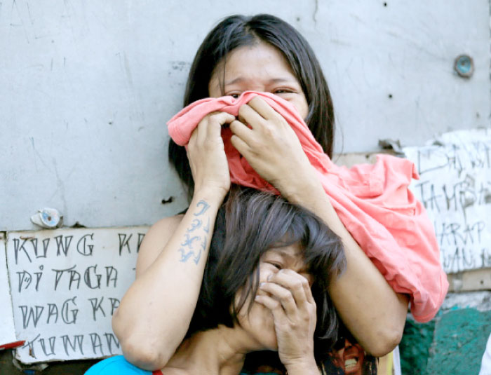 Relatives of a suspected drug pusher, who was shot and killed by unidentified men, react upon learning that their kin was killed in Quezon city, metro Manila, Philippines, on Tuesday. — Reuters