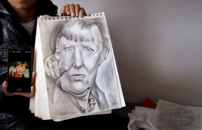 Farhad Nouri poses with a drawing of German Chancellor Angela Merkel in his room in the “Krnjaca” collective centre near Belgrade, Serbia on  Tuesday. - AP