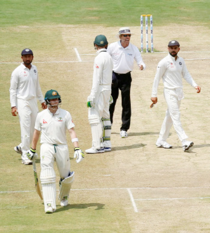 Umpire speaks to India’s captain Virat Kohli (R) as Australia’s captain Steven Smith (2nd L) walks off the ground after being dismissed during the second cricket Test match at the M. Chinnaswamy Stadium, Bengaluru, Tuesday. — Reuters