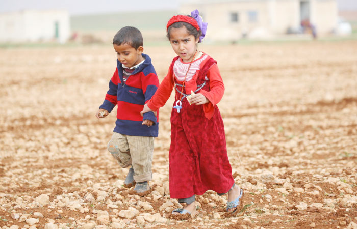 Displaced Syrian children, who fled their hometowns due to clashes between regime forces and the Daesh group, walk in a field in Kharufiyah, 18 kilometers south of Manbij. — AFP