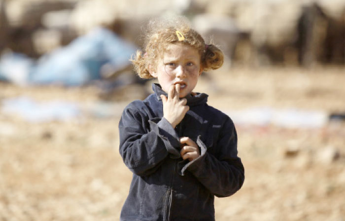 A Syrian child stands at a makeshift camp for displaced people near the town of Manbij. — AFP