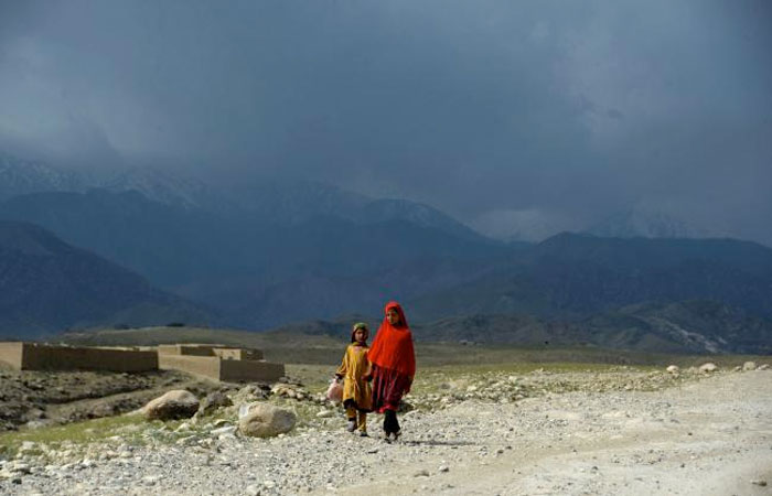 Afghan girls walk through a village near the site of a bomb attack by US forces in the Achin district of Nangarhar province. — AFP