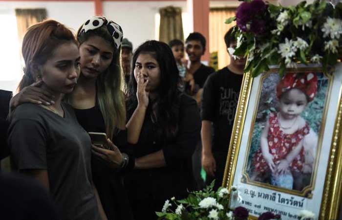 Jiranuch Trirat, left, 22, is comforted by friends as she looks at a photograph of her 11-month-old daughter Natalie during the last funeral rites at a temple in Phuket, Thailand, on Saturday. — AFP