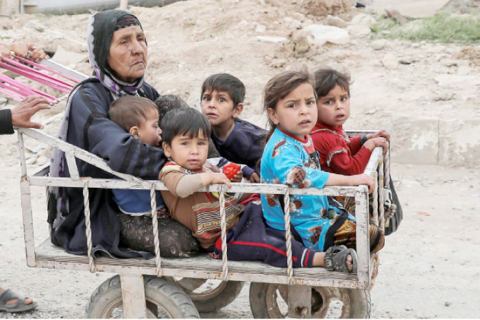 A displaced Iraqi woman and children are transported in a cart as the battle between the Iraqi Counter Terrorism Service and Daesh militants continues nearby, in western Mosul, Iraq. — Reuters