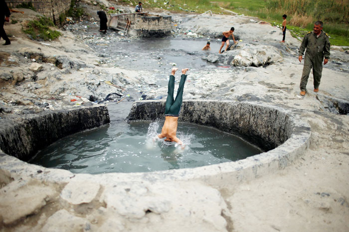 An Iraqi boy jumps into a sulfur pond at Hammam Al-Alil city south of Mosul, Iraq. — Reuters