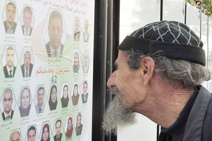 A passerby looks at electoral campaign posters for the upcoming legislative election in Algiers, Algeria. — AP