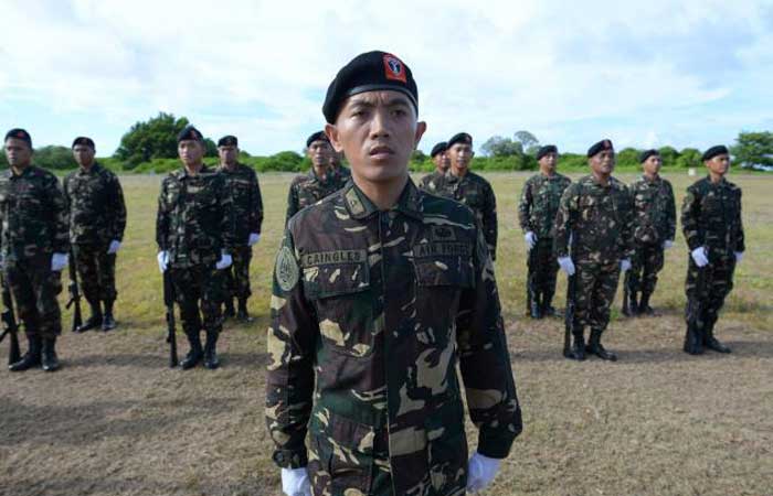 Philippine soldiers stationed at Thitu island stand at attention as they sing as part of the welcome ceremony program for Defense Secretary Delfin Lorenzana during a visit to the island in he Spratlys on Friday. — AFP