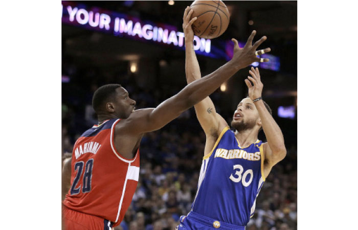 Golden State Warriors' Stephen Curry, right, lays up a shot past Washington Wizards' Ian Mahinmi (28) during the second half of an NBA basketball game Sunday  in Oakland, Calif. Warriors won, 139-115. — AP