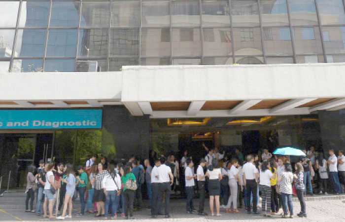 Office workers stand on the grounds of an office building in the financial district of Makati in Manila on Saturday, after a 5.7 magnitude earthquake. — AFP