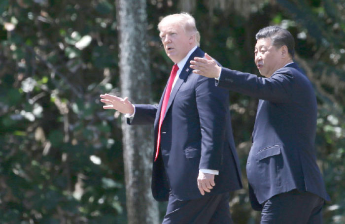 US President Donald Trump, left, and China’s President Xi Jinping walk along the front patio of the Mar-a-Lago estate after a bilateral meeting in Palm Beach, Florida, on Friday. — Reuters