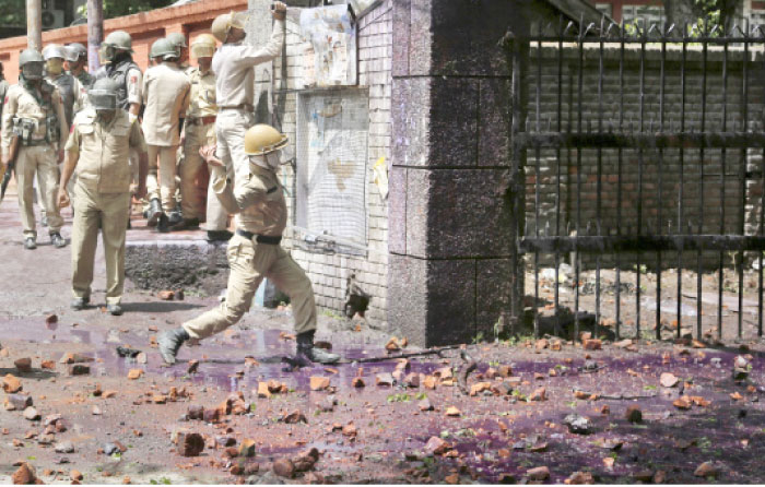 An Indian police man throws stones at Kashmiri student protesters as they clash in Srinagar, Indian controlled Kashmir, on Monday. — AP