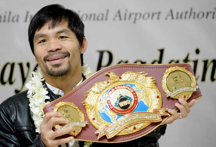 This file photo shows Filipino boxer Manny Pacquiao holding his championship belt as he arrives at Manila International Airport in Manila. — AFP