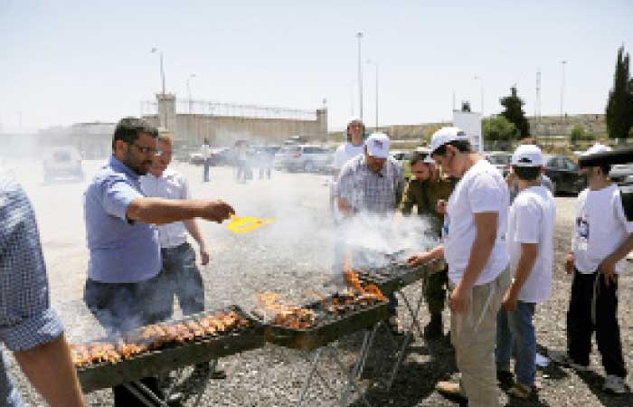 Israelis have a BBQ outside Ofer Prison while Palestinians rally in support of Palestinian prisoners on hunger strike in Israeli jails over the fence, outside Ofer Prison near the West Bank city of Ramallah. — Reuters