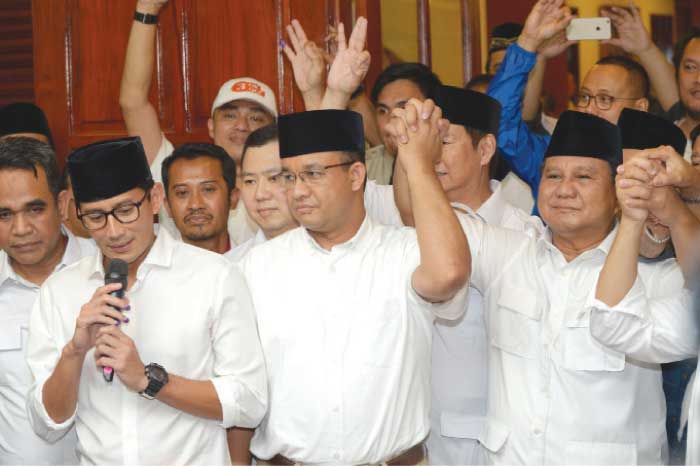 Jakarta governor-elect Anies Baswedan (center), his deputy governor-elect Sandiaga Una (left) and Prabowo Subianto (right) of the Gerindra party hold hands together during a press conference in Jakarta, Wednesday. — AFP