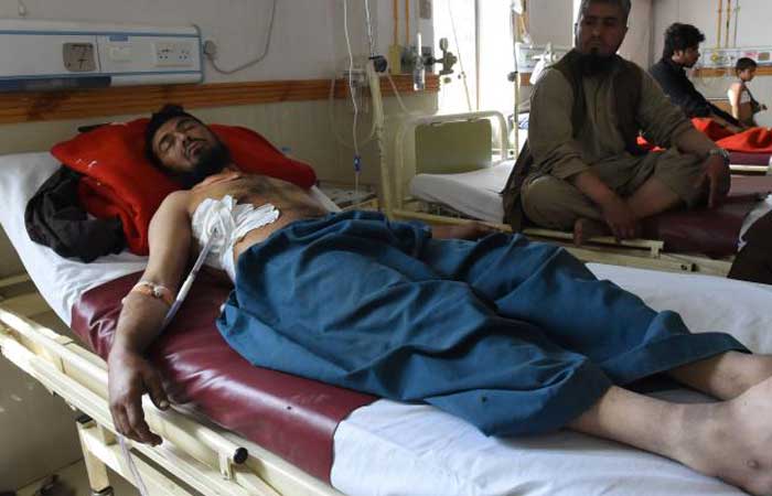 A Pakistani relative sits next to an injured victim of cross border firing, at a hospital in Quetta on Friday. — AFP
