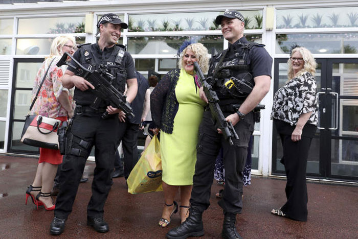 Race goers interact with armed police inside Haydock Park Racecourse in Haydock, England, on Saturday. — AP