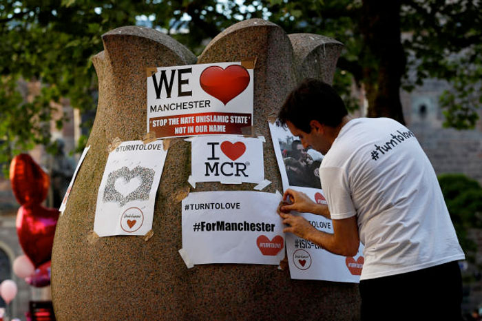 A man attaches a placard on a fountain in St Ann's Square, in central Manchester, Britain. — Reuters