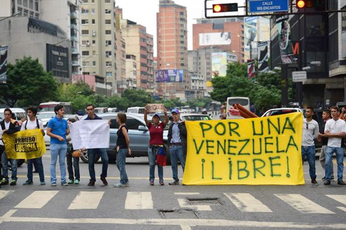 Demonstrators display a banner as they block a street during a protest against Venezuelan President Nicolas Maduro in Caracas. — AFP