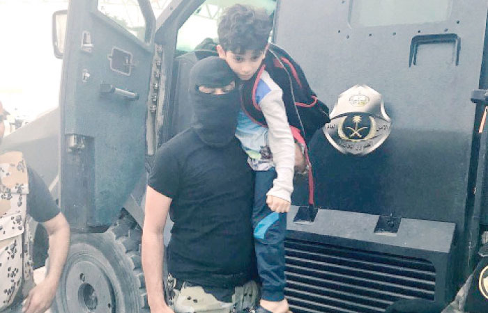 A Saudi security man hugs a boy from Al-Awamiyah’s Al-Masourah area after a security operation.