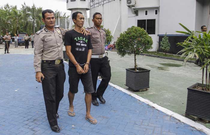 Police officers escort a captured inmate following a prison break at the Sialang Bungkuk Prison in Pekanbaru, Riau province, Indonesia, on Saturday. — AP