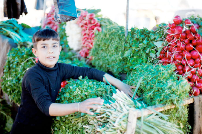 Falah, 12, sells vegetables and fruits in a market in eastern Mosul. — Reuters
