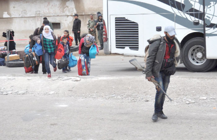 Syrian opposition fighters and their families prepare to board a bus at a checkpoint manned by regime forces ahead of their evacuation from Al-Waer neighborhood, the last opposition-held district in the central city of Homs, on Saturday. — AFP