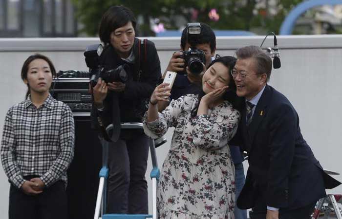 South Korea’s presidential candidate Moon Jae-in, right, from the Democratic Party takes pictures with a supporter during an election campaign in Seoul on Saturday. — AP