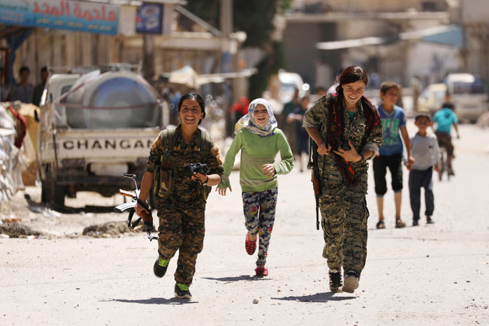 Syrian Democratic Forces (SDF) women fighters run with chidlren in the town of Tabqa, after SDF captured it from Daesh this week. — Reuters