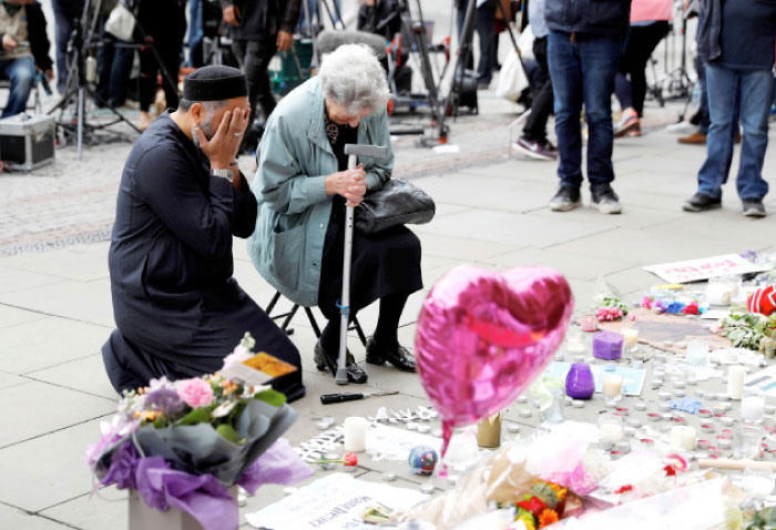 A Jewish woman named Renee Rachel Black and a Muslim man named Sadiq Patel react next to floral tributes in St Ann’s Square in Manchester on Wednesday. — Reuters