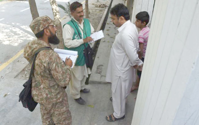 An official of the Pakistan Bureau of Statistics, second left, and a soldier collect information from a resident during a census at Rabwah in Chiniot District in Punjab province, Pakistan, in this March 27, 2017 file photo. — AFP